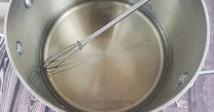 Water in saucepan with whisk.