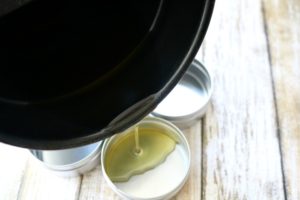 Pouring menstrual cram pain relief salve into metal tins