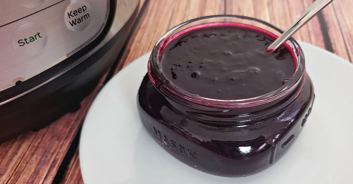 Blueberry jam in mason jar next to Instant Pot.