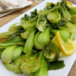 Close up of two boy choy halves roasted on a pan with more in the background