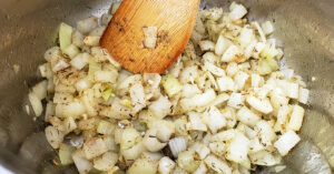 Sea salt, garlic powder, black pepper, sage and thyme being added to cooking onions and garlic in Instant Pot.