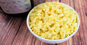 Gluten free mac and cheese in serving bowl next to Instant Pot.