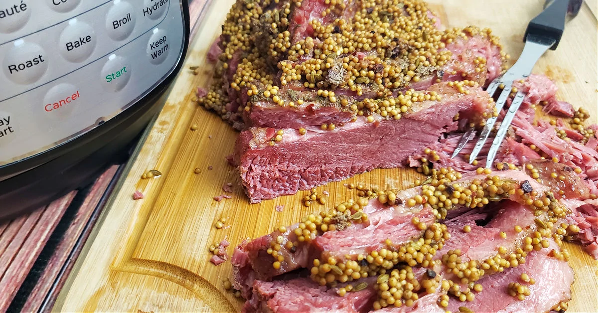 Sliced corned beef on cutting board with serving fork.