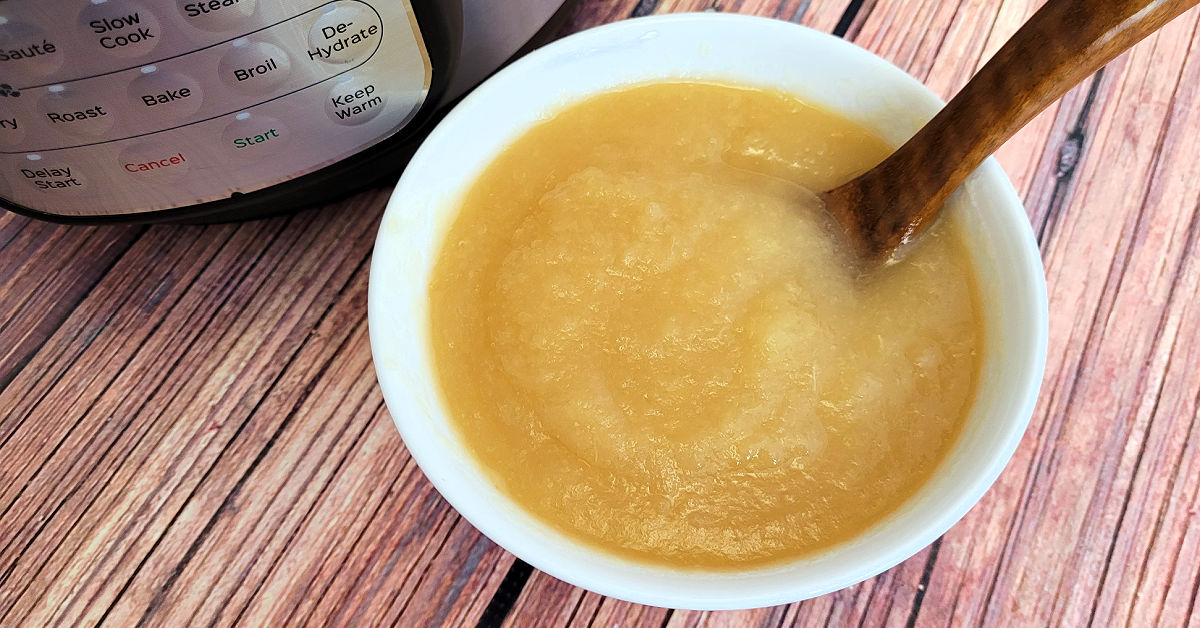 Bowl of homemade applesauce next to the Instant Pot it was made in.